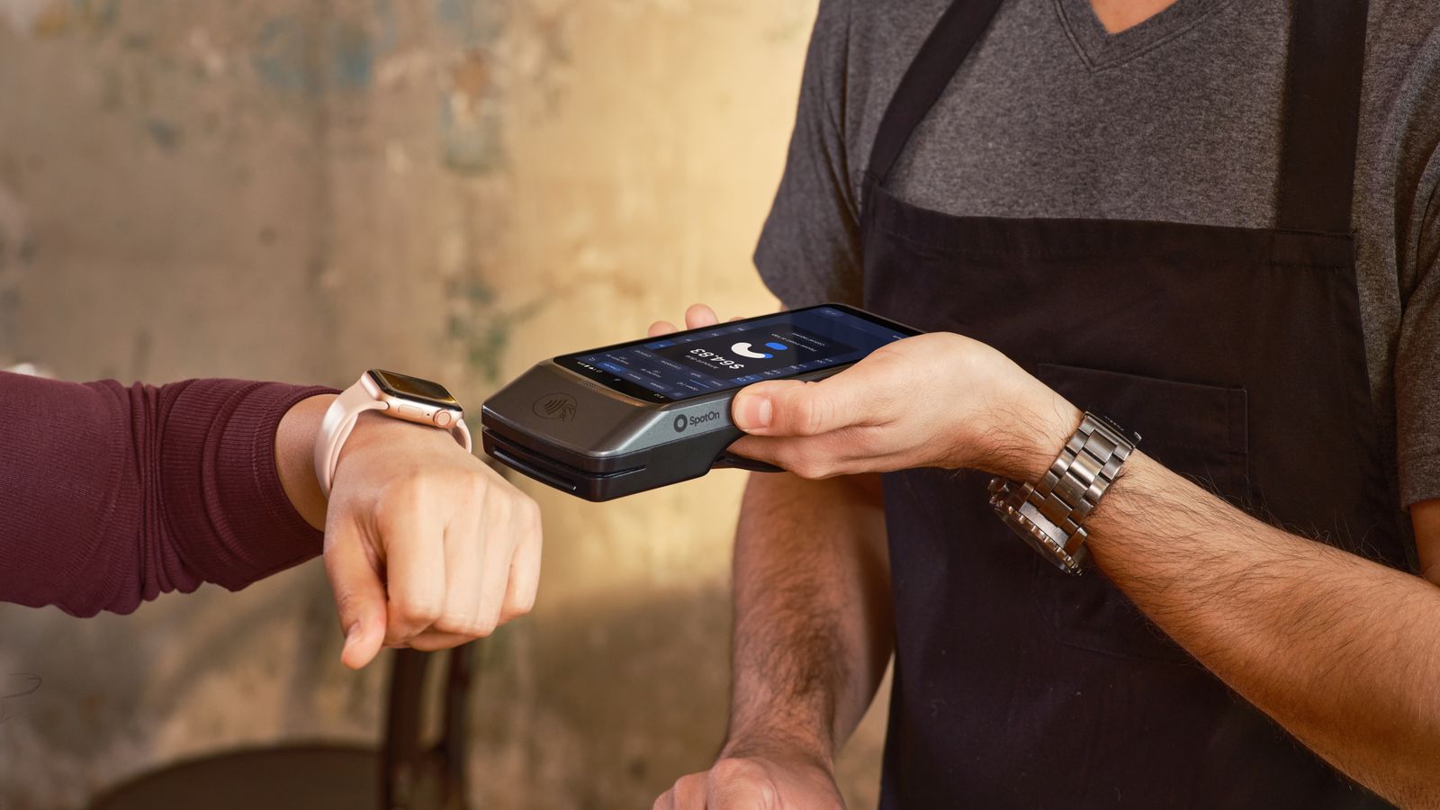 Smartwatch user making a contactless payment at a café using a POS device.