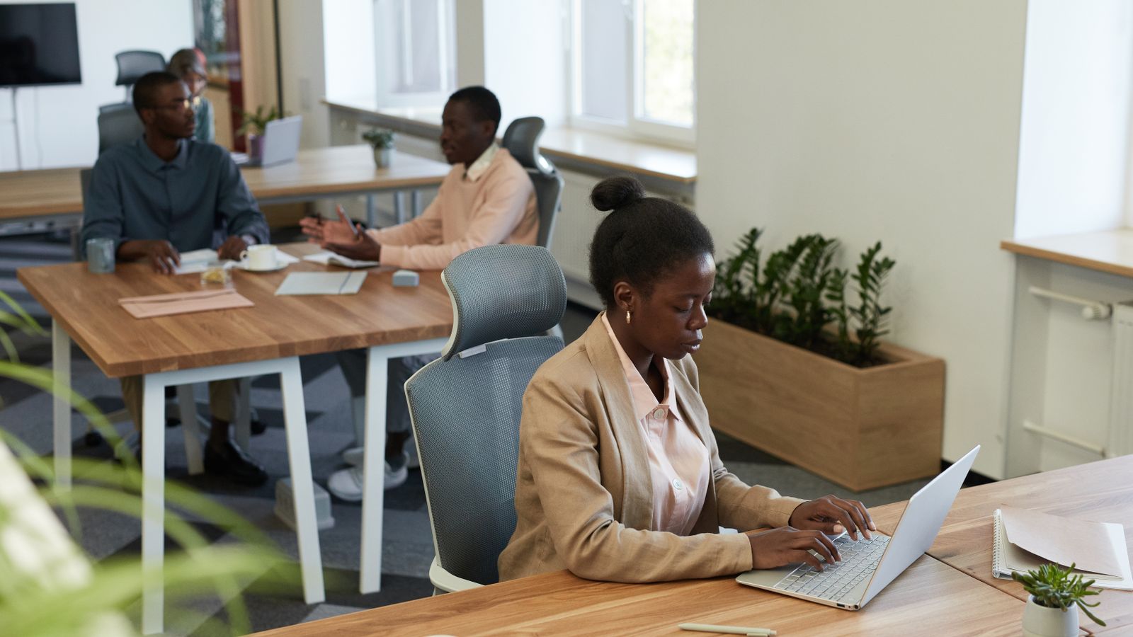 Diverse group of professionals collaborating in a modern office setting with laptops and discussions.