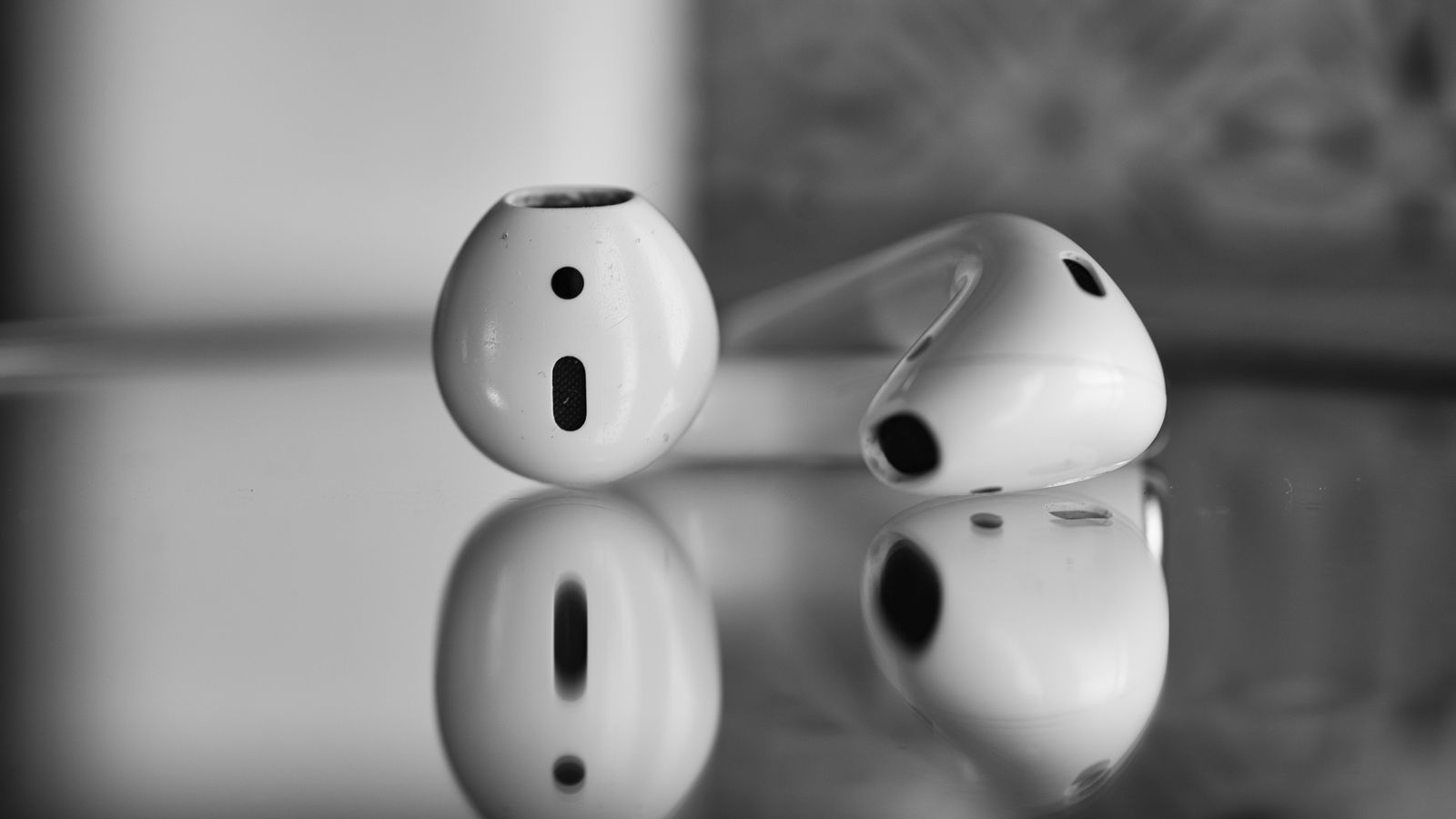 Close-up of wireless earbuds with reflection in black and white.
