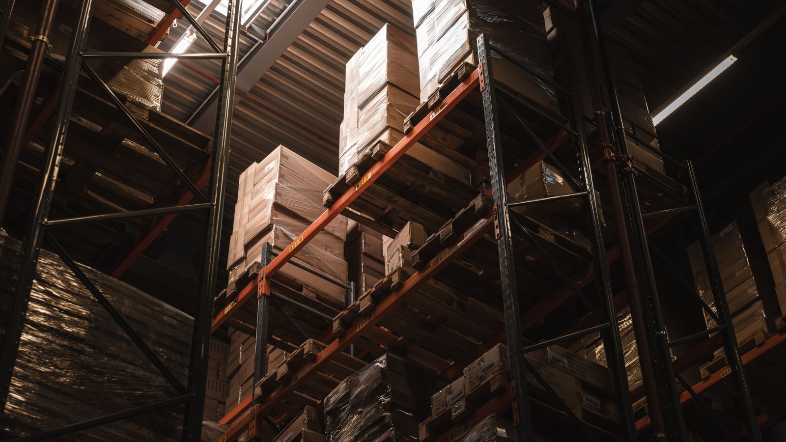 Interior view of a warehouse with stacked cardboard boxes on high shelves, showcasing storage and logistics.