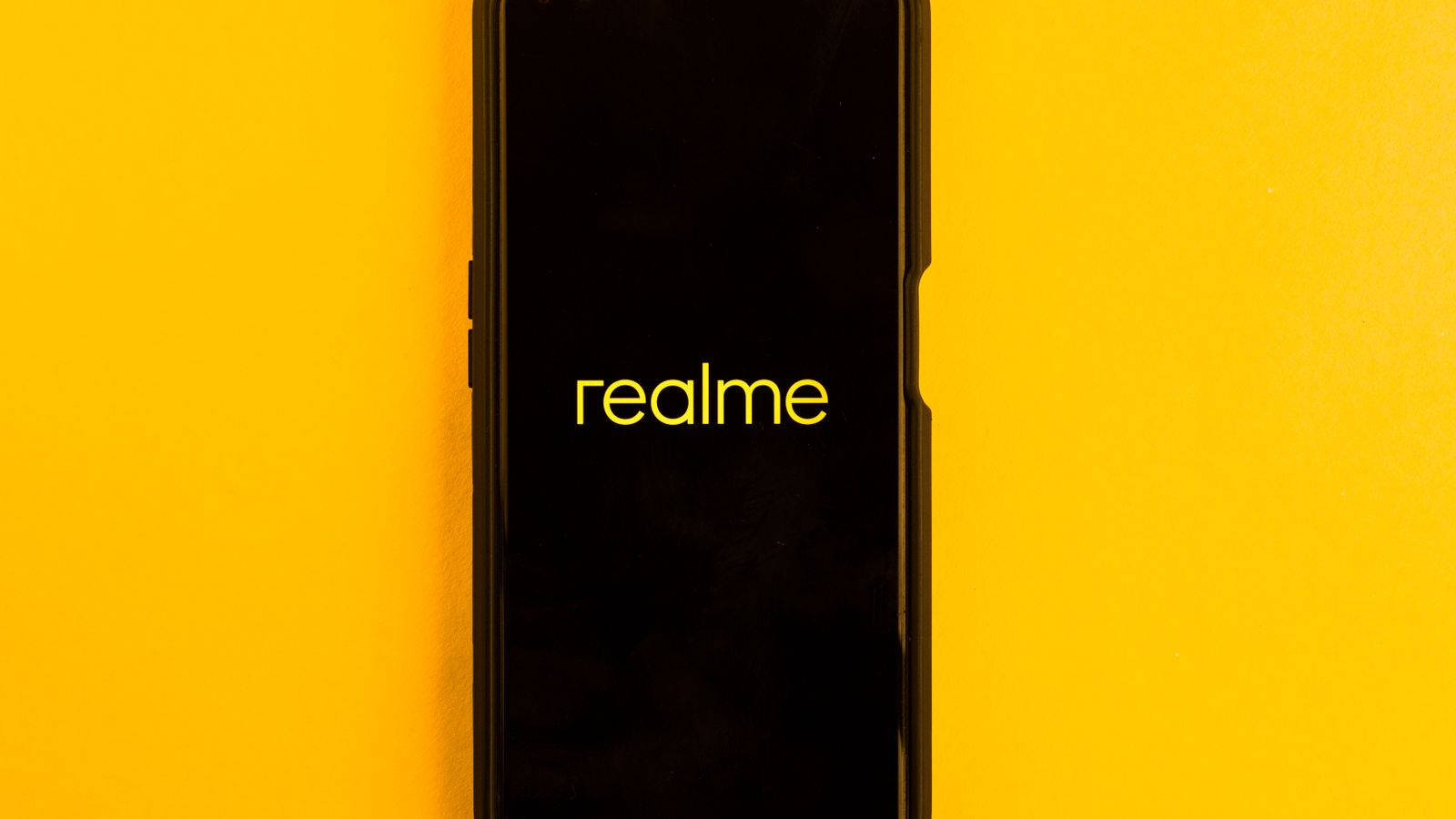 Realme smartphone displayed against a bright yellow backdrop, emphasizing modern technology.