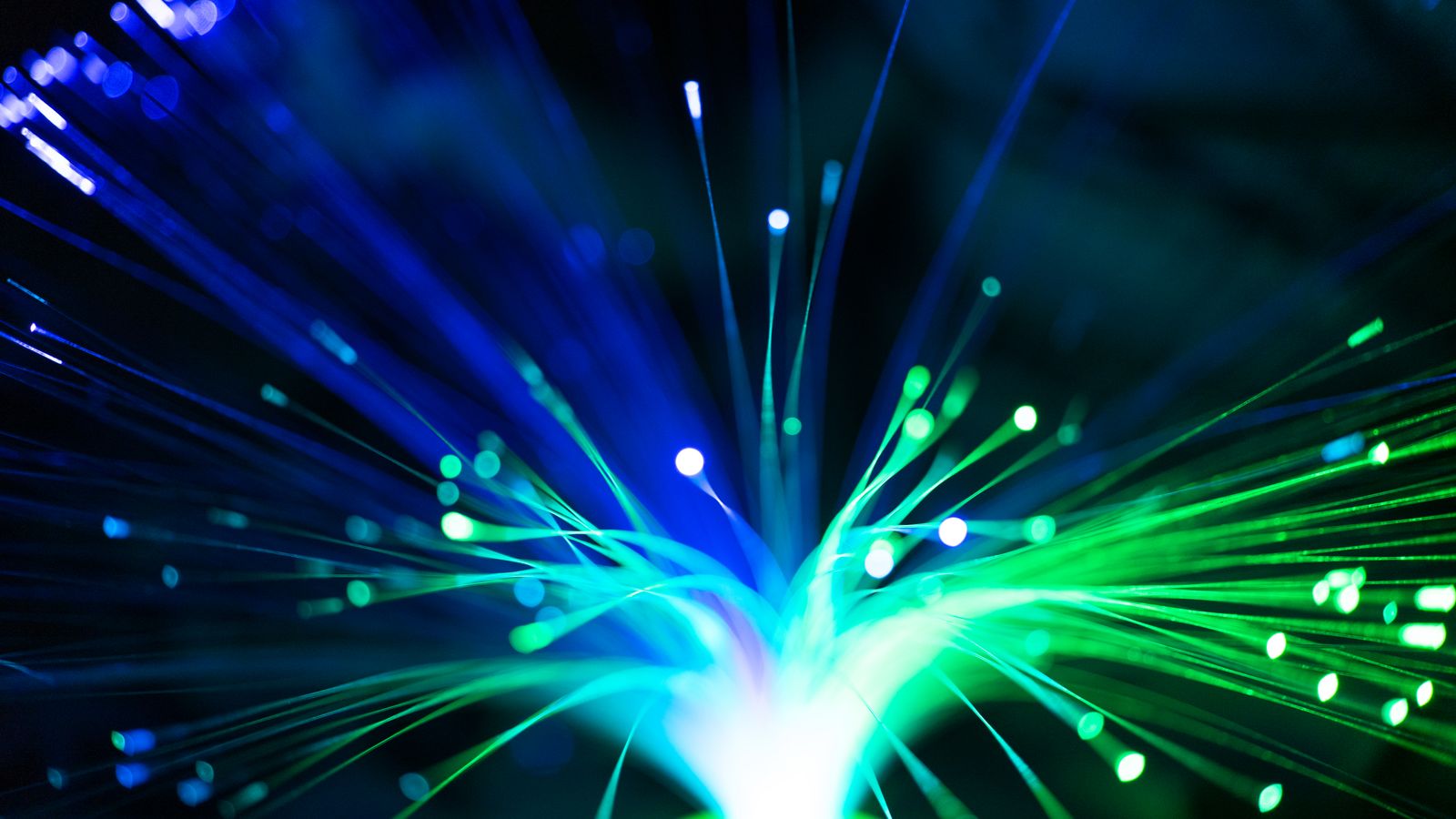 Close-up of illuminated fiber optic lights in blue and green colors, showcasing modern technology.