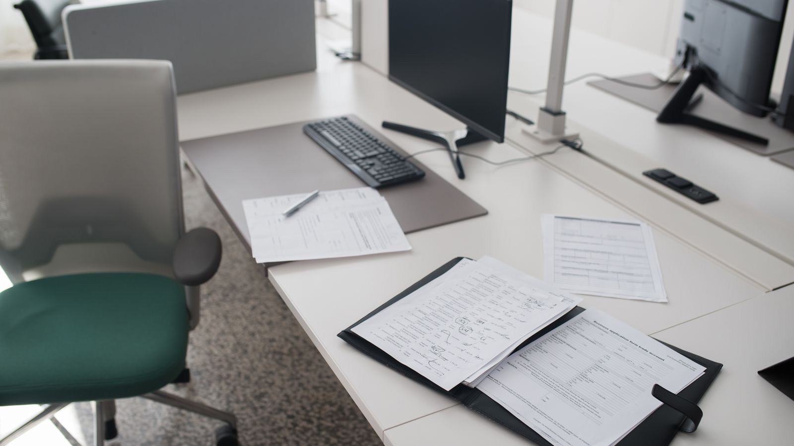 A clean and organized office desk with documents, a computer, and chair in a modern workspace.
