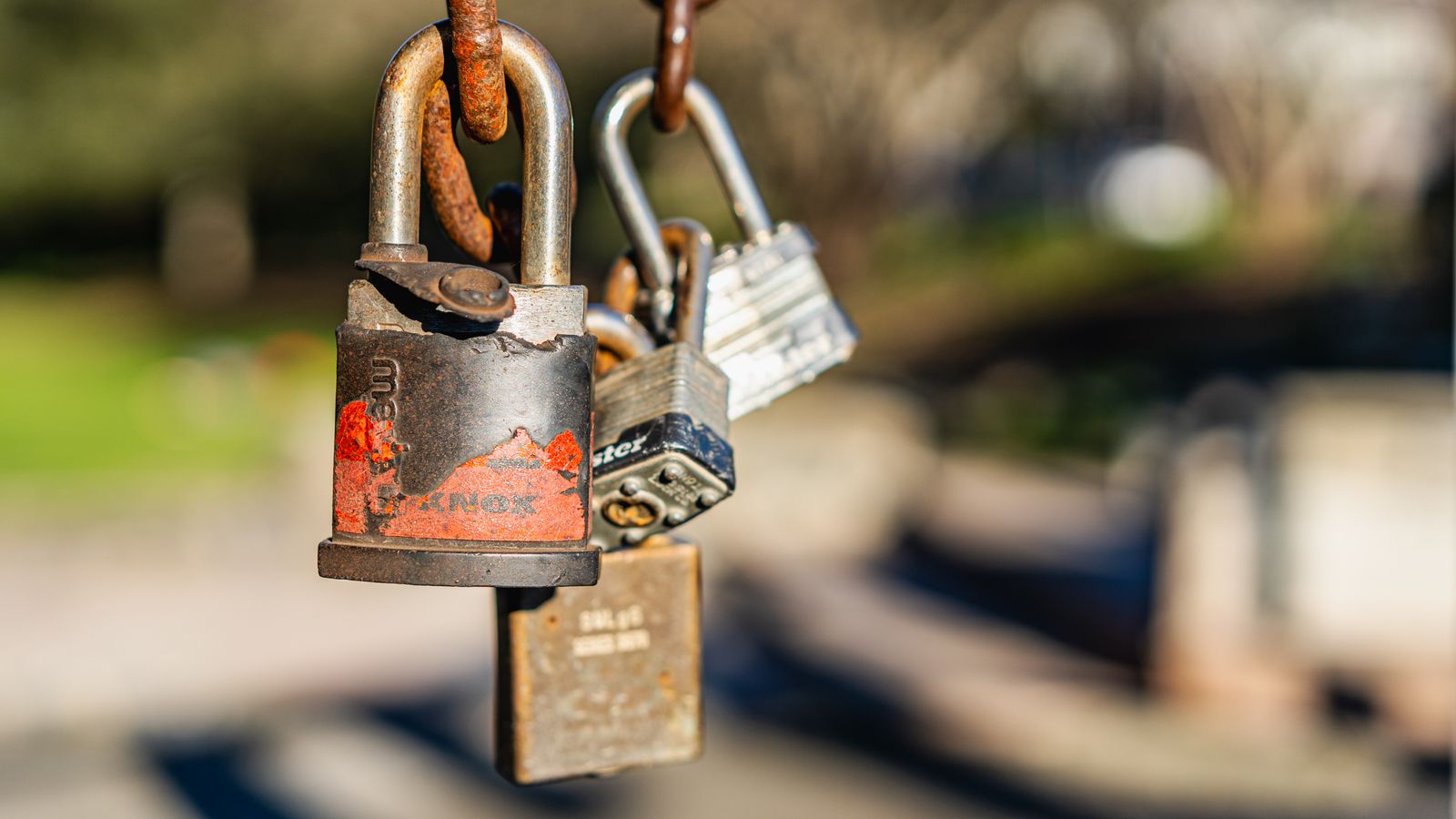 Macro shot of rusty padlocks hanging on a chain, symbolizing security and neglect.