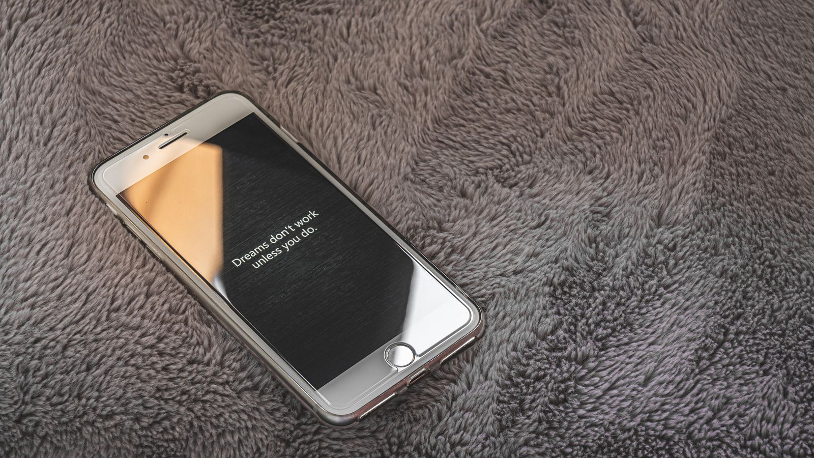 A smartphone displaying an inspirational quote on a cozy gray blanket, perfect for themes of motivation and relaxation.