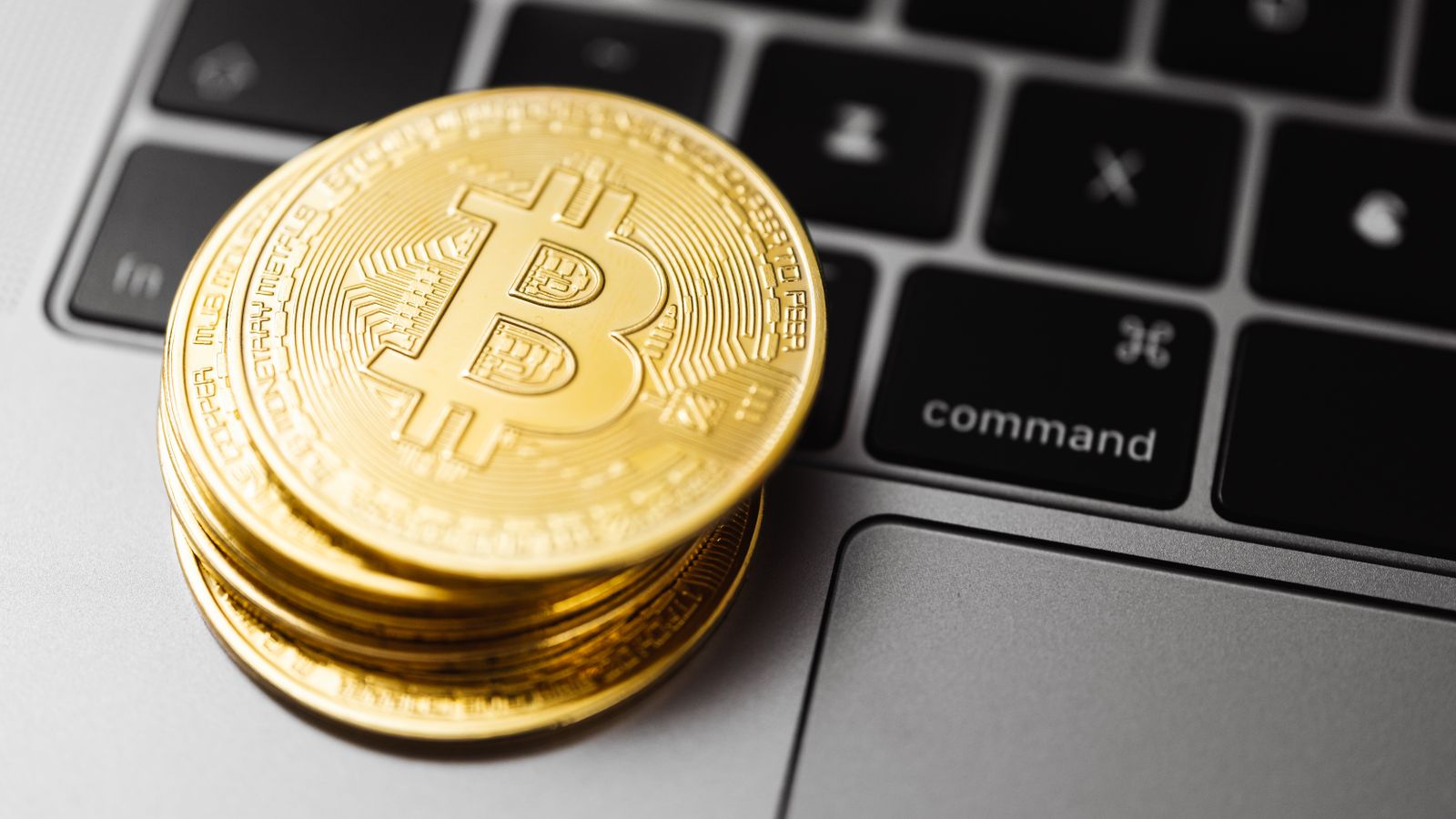 Close-up of gold bitcoin coins on a laptop keyboard, symbolizing digital currency and technology.