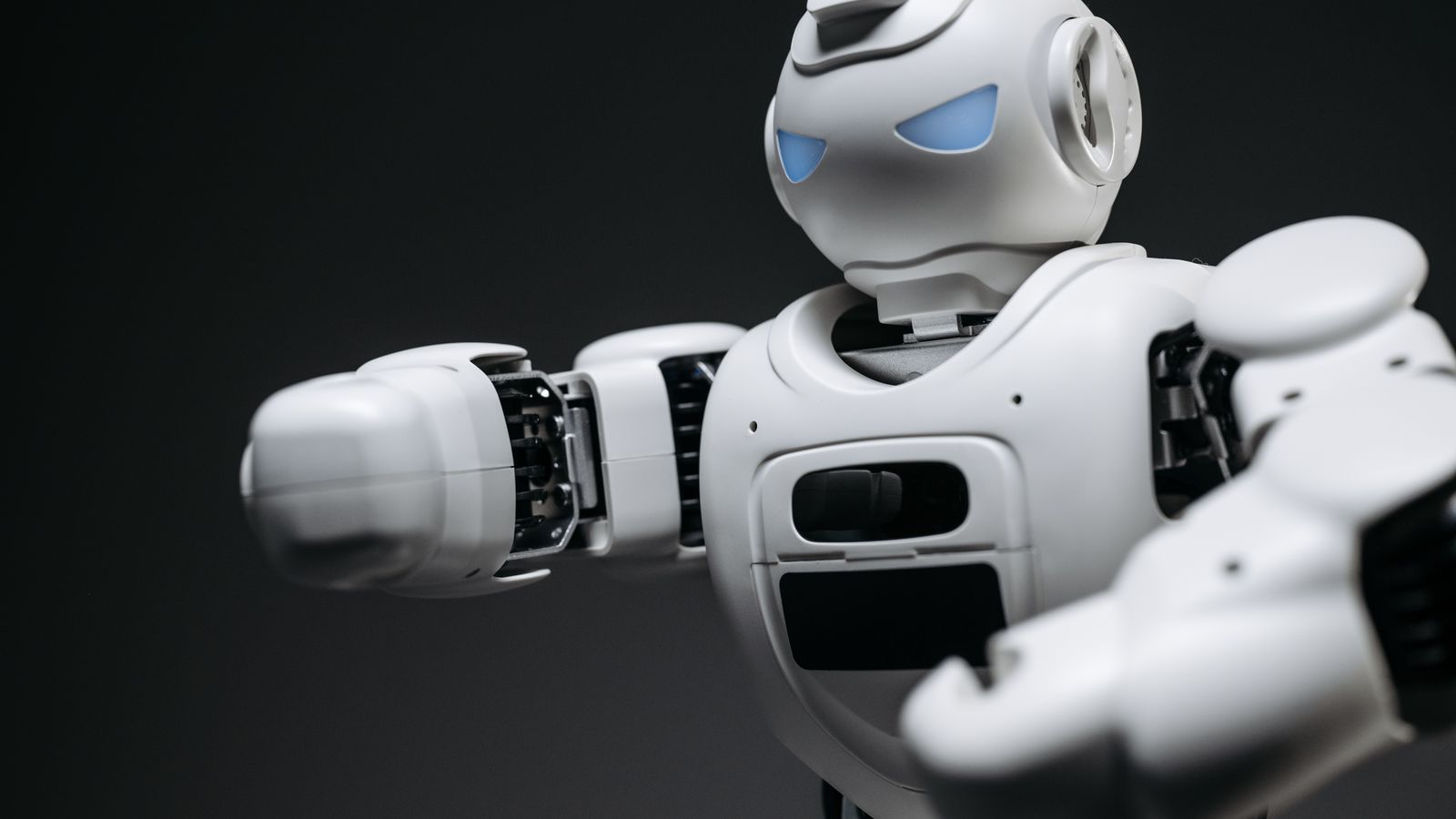 Detailed close-up of a high-tech white robot in a studio setting with a gray background.