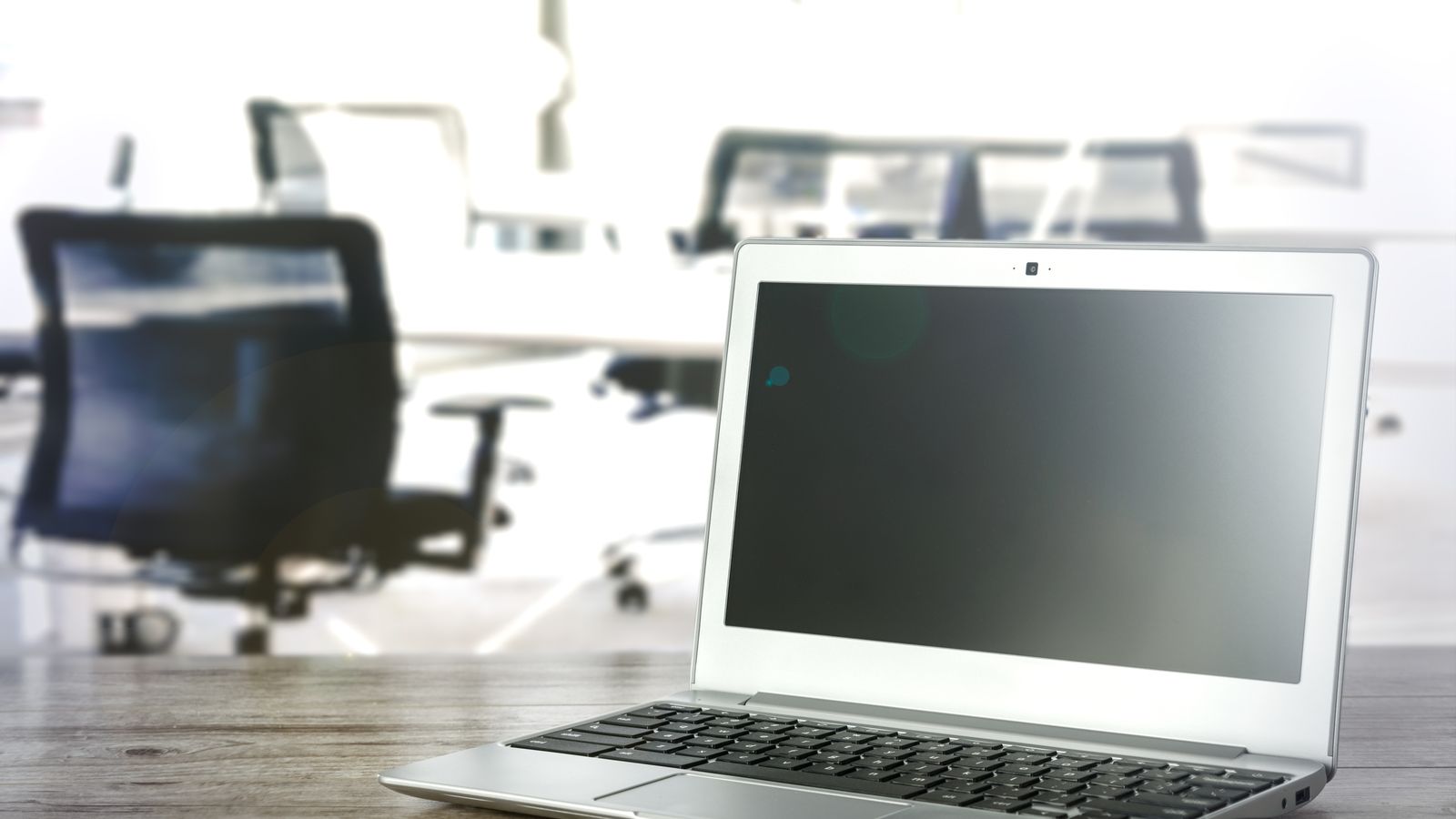 A sleek laptop on a desk in a bright and modern office setting.