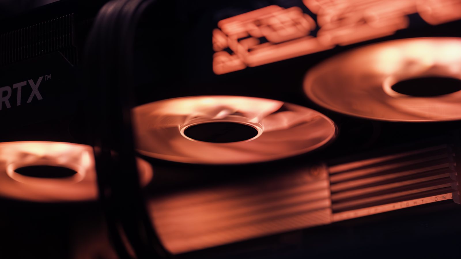 Dynamic close-up shot of illuminated gaming graphics card fans in red light, showcasing cutting-edge technology.