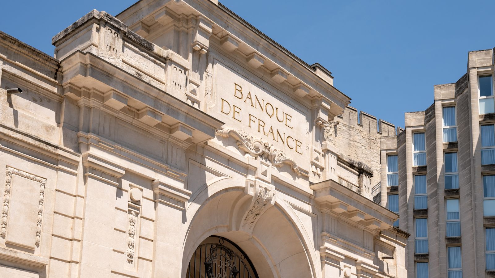 Elegant architectural facade of Banque de France in Avignon against clear blue sky.