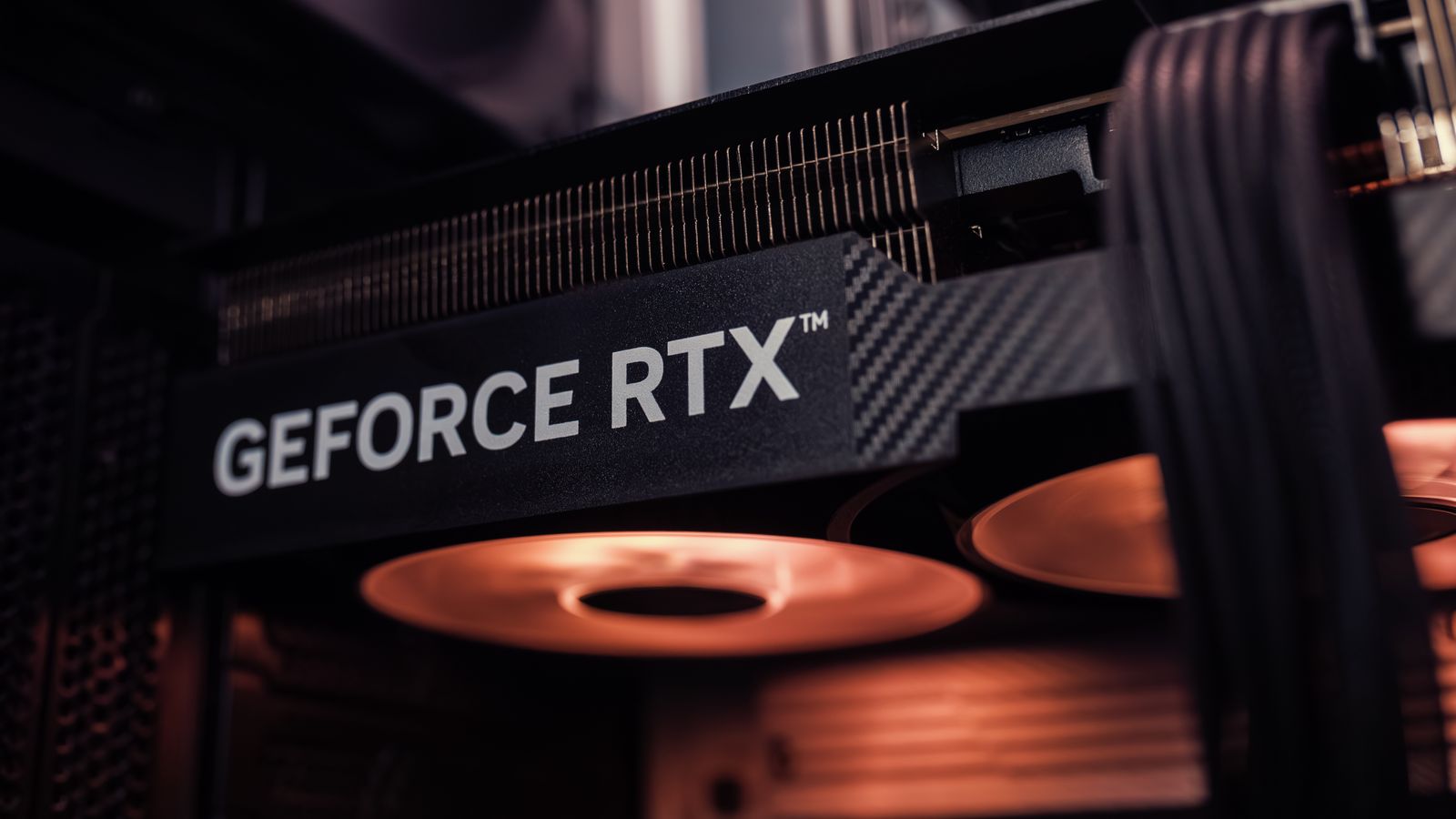 GeForce RTX graphics card installed inside a PC, glowing under warm lighting.