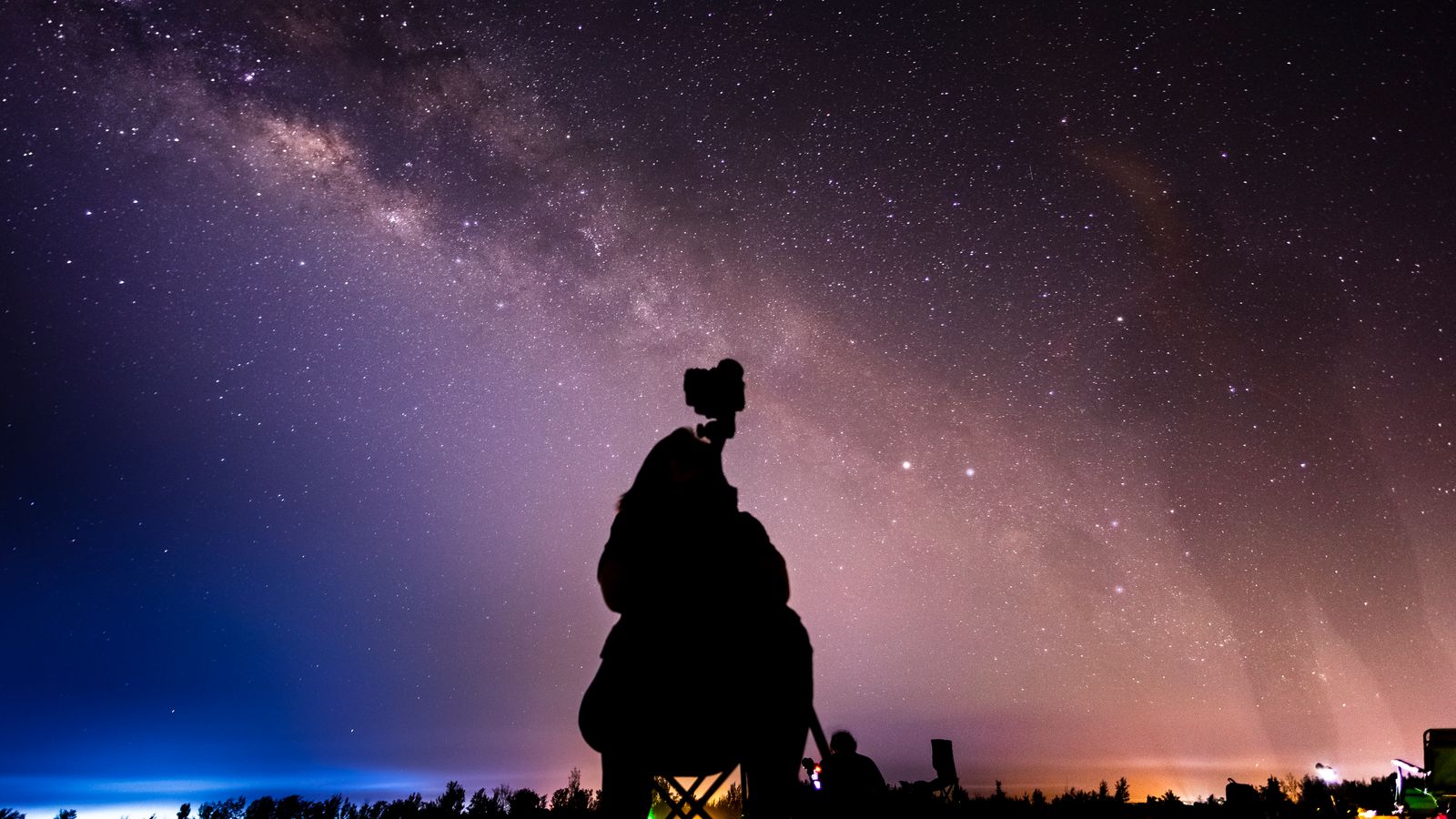 A lone stargazer with a flashlight stands under mesmerizing star trails in Gola, Croatia.