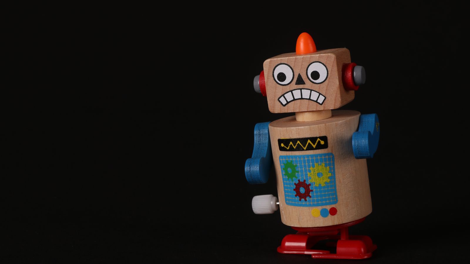 A vibrant wooden toy robot stands on a dark surface, showcasing vivid colors and playful design.