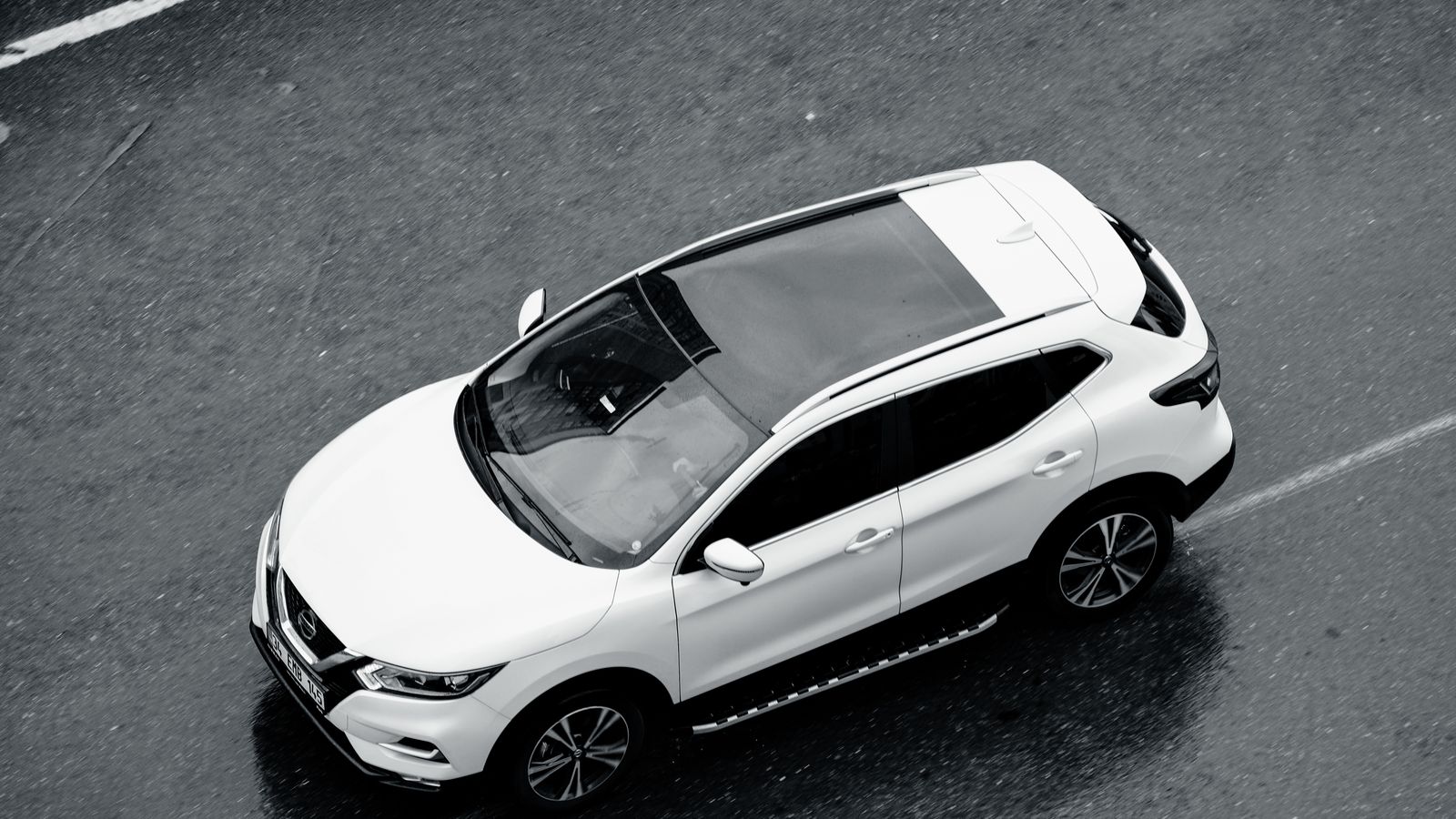 A white SUV is seen from above cruising along the wet streets of Istanbul, Turkey.