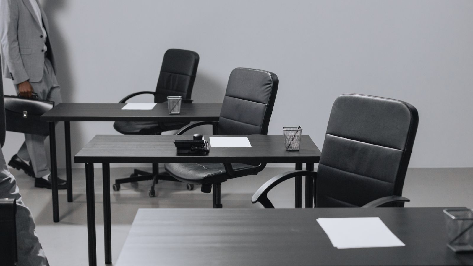 Contemporary office space with black leather chairs and desks, showcasing a minimalist design.