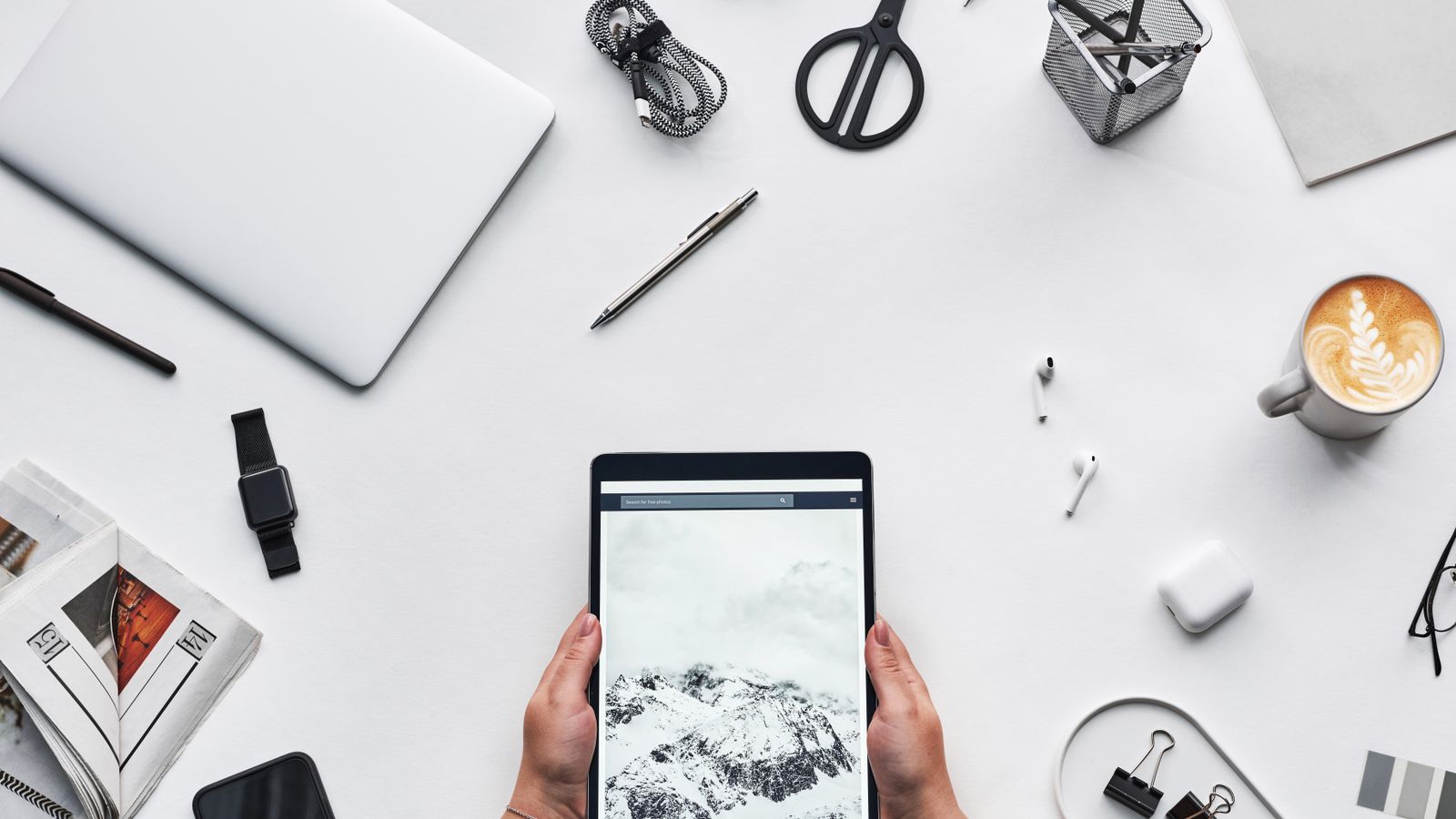 Flat lay of a modern workspace featuring a tablet, gadgets, and coffee for creative work.