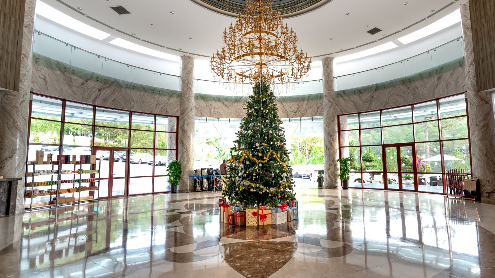 Spacious hotel lobby featuring a beautifully decorated Christmas tree and elegant chandelier.
