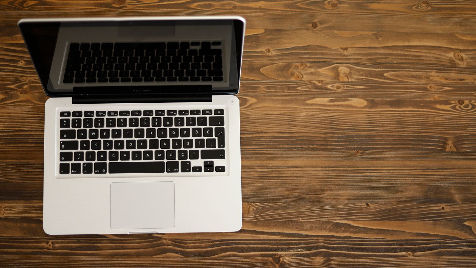 Aerial view of an open laptop on a rustic wooden desk, ideal for technology themes.