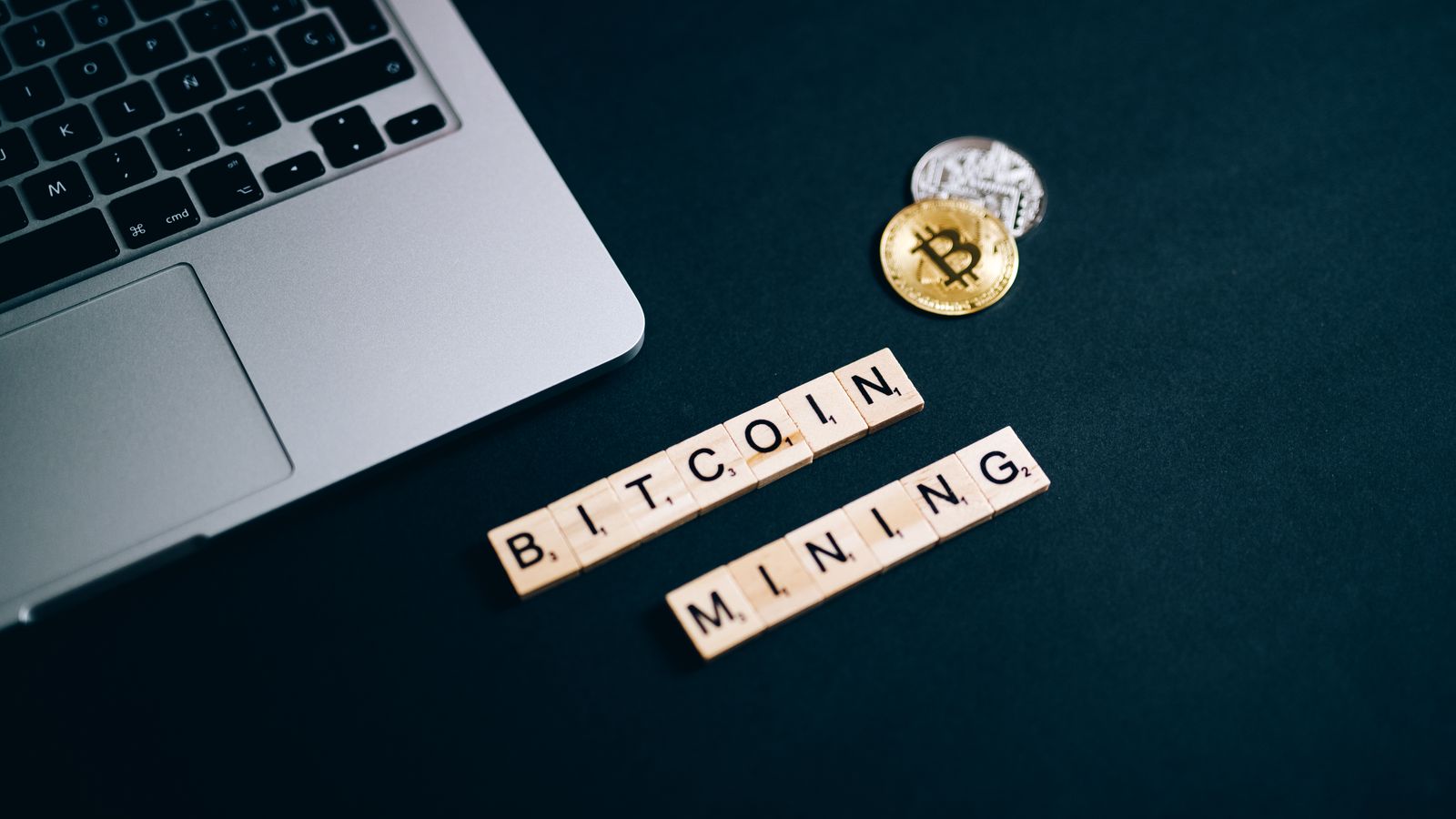 Top view of Bitcoin mining concept represented with laptop keyboard and Scrabble tiles.