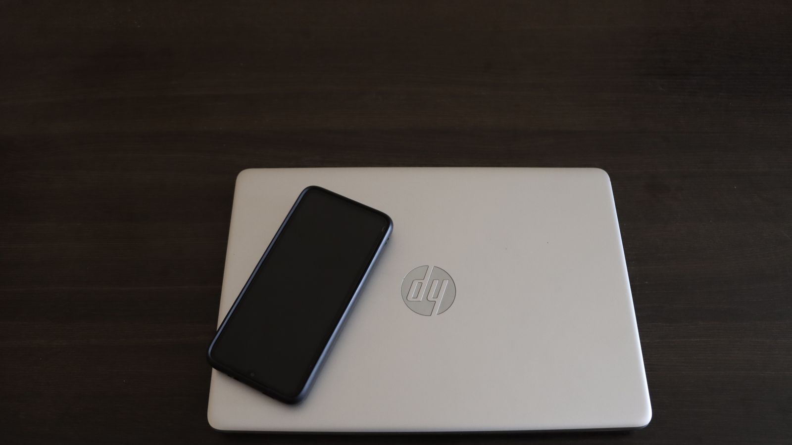 Close-up of a smartphone resting on an HP laptop, symbolizing modern technology integration.