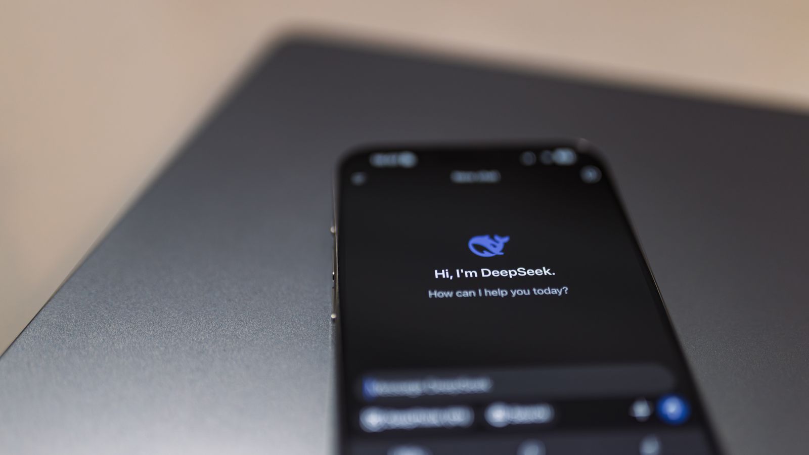Close-up of a smartphone with AI assistant interface on screen over a laptop.
