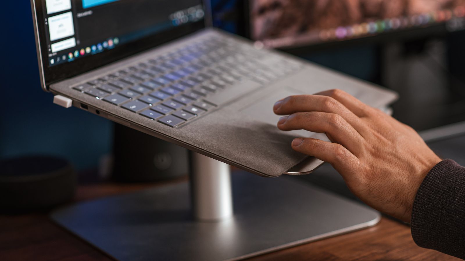 Crop unrecognizable male browsing modern netbook and scrolling touchpad placed on stand on desk