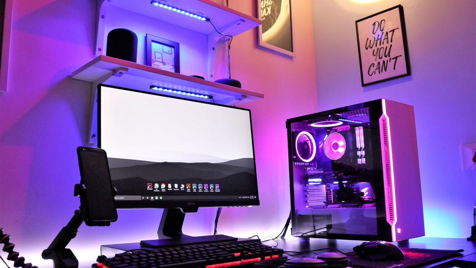 A sleek gaming setup featuring RGB lighting with a desktop, monitor, and smartphone in a vibrant room.