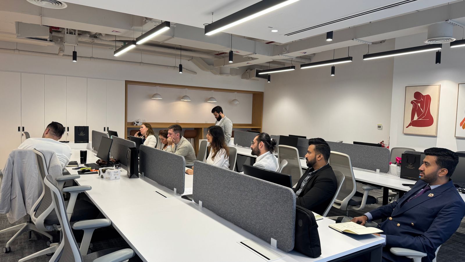 Diverse team working in a modern office setting with computers and collaborative spaces.