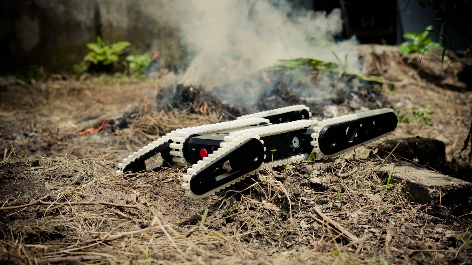 A robotic crawler navigates through dirt and grass, showcasing technology in nature.