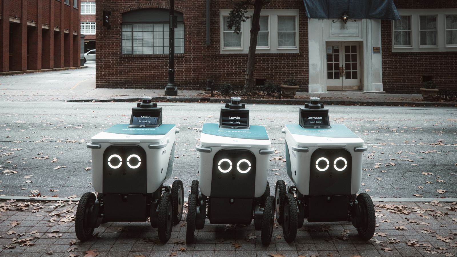 Autonomous delivery robots positioned on an urban street, showcasing technology in modern logistics.