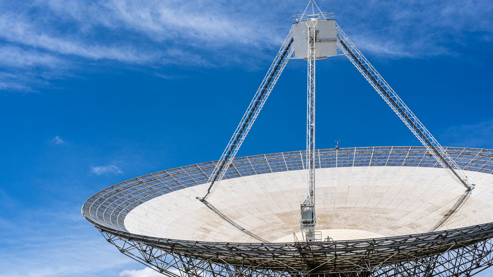 A large satellite dish with a clear blue sky in the background, showcasing modern communication technology.