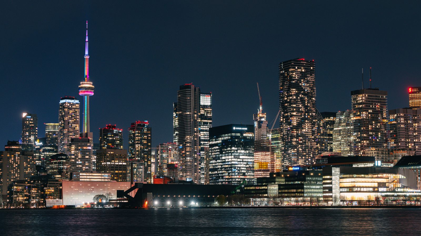 Vibrant night view of Toronto skyline featuring the illuminated CN Tower reflecting on the water.
