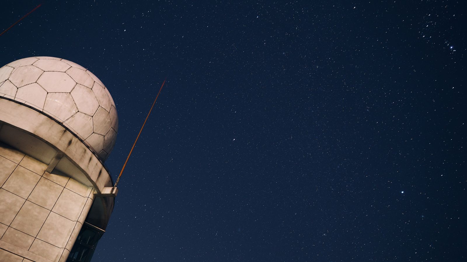 Large radio telescope beneath an arc of the Milky Way at dusk