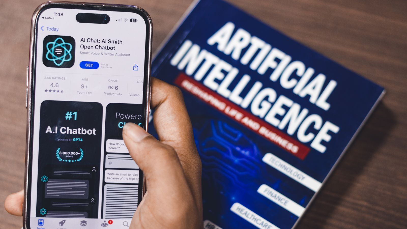 Smartphone displaying AI app with book on AI technology in background.