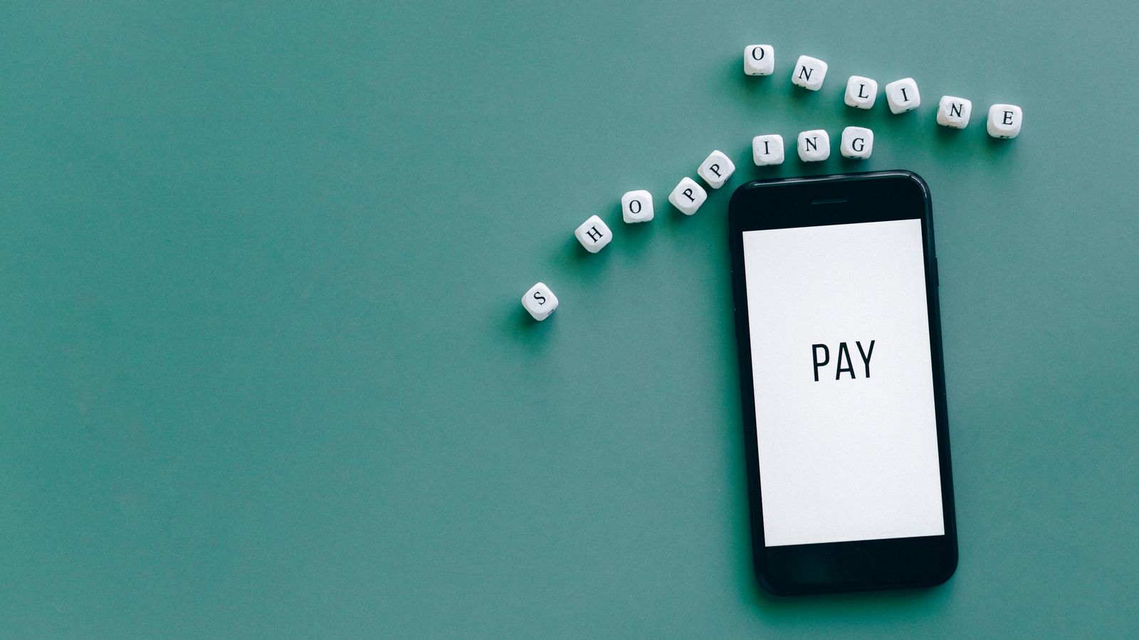Image of smartphone displaying 'PAY' surrounded by dice spelling 'online shopping' on teal background.