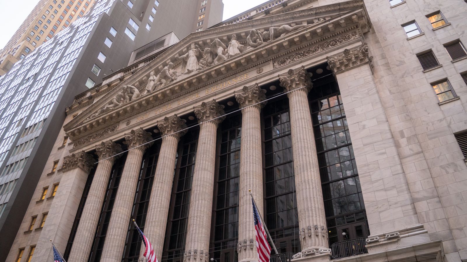 Close-up view of the iconic New York Stock Exchange building with American flags, located in Wall Street, NYC.