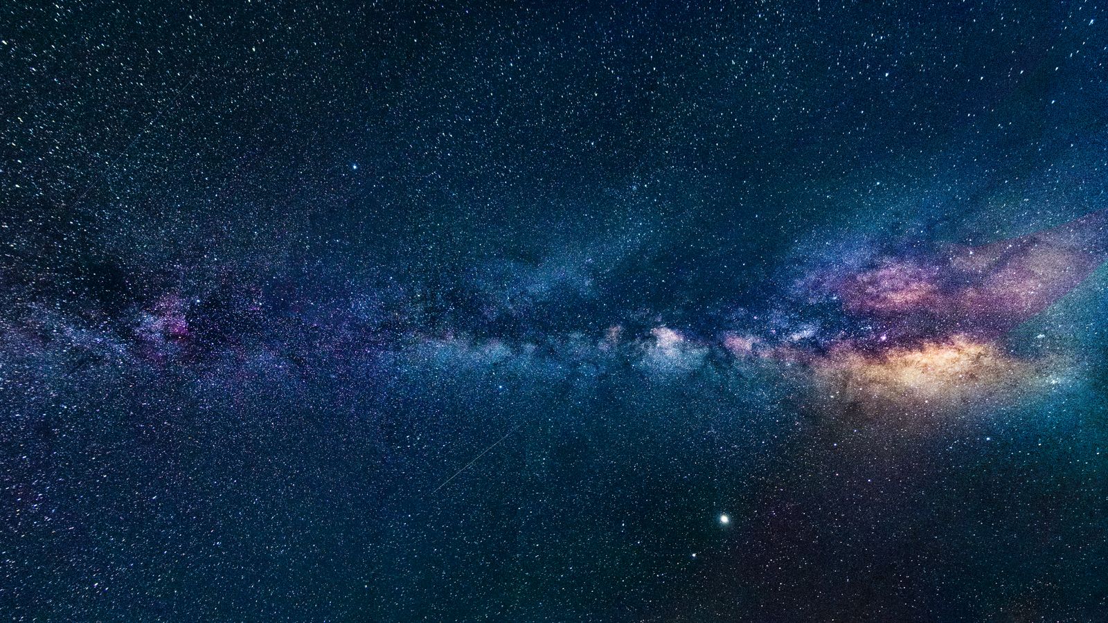 Capture of the Milky Way galaxy stretching across the dark night sky, filled with stars.