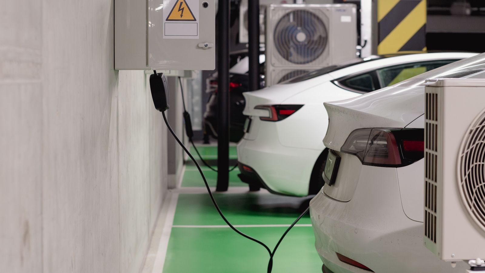 Electric vehicles charging at an indoor station in a modern underground garage.