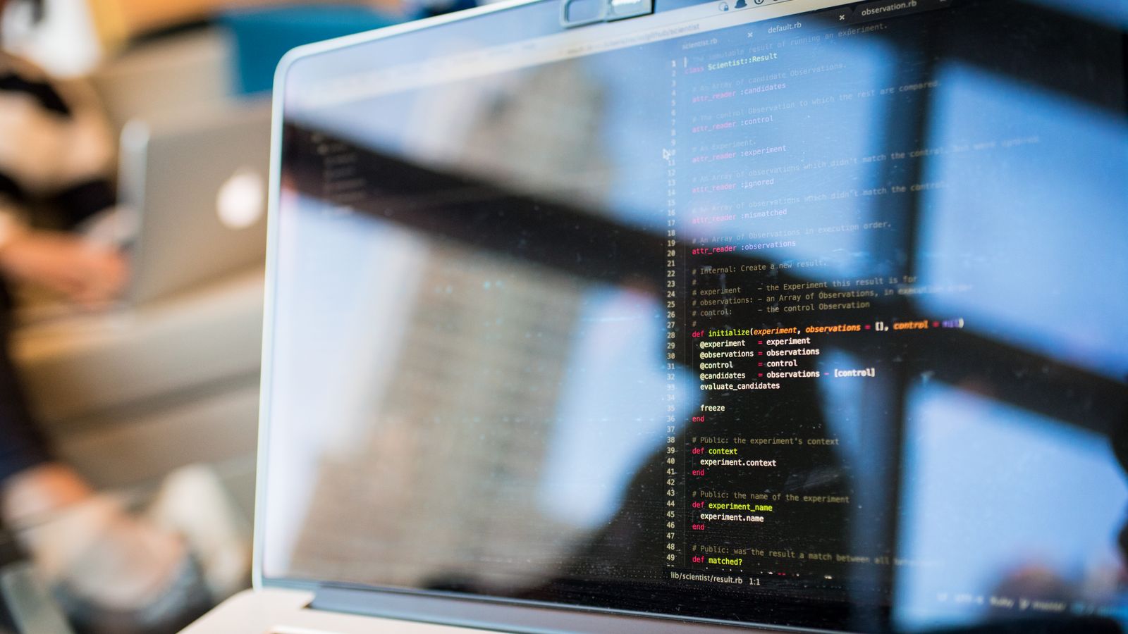 Laptop displaying code with reflection, perfect for tech and programming themes.