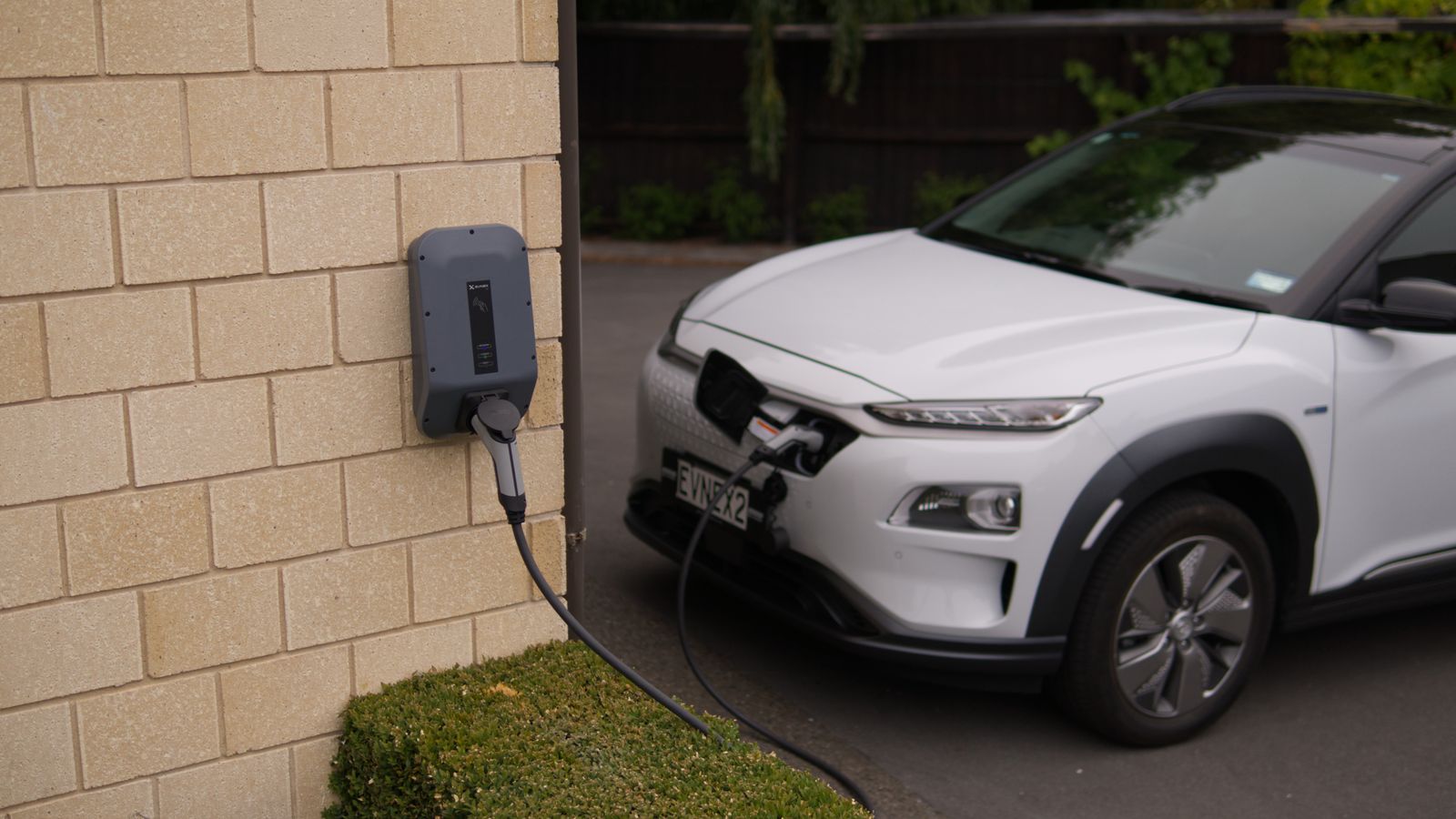 A white electric car charging at a station in Christchurch, New Zealand, showcasing modern eco-friendly transportation.