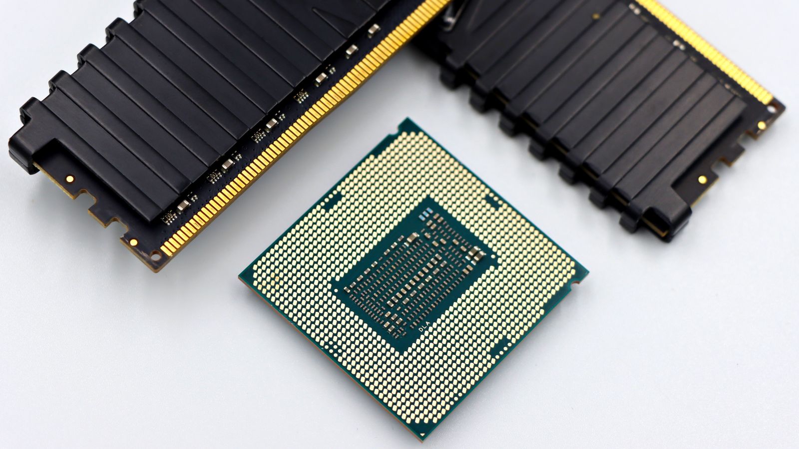 A CPU and RAM sticks displayed on a white surface, showcasing computer hardware components.