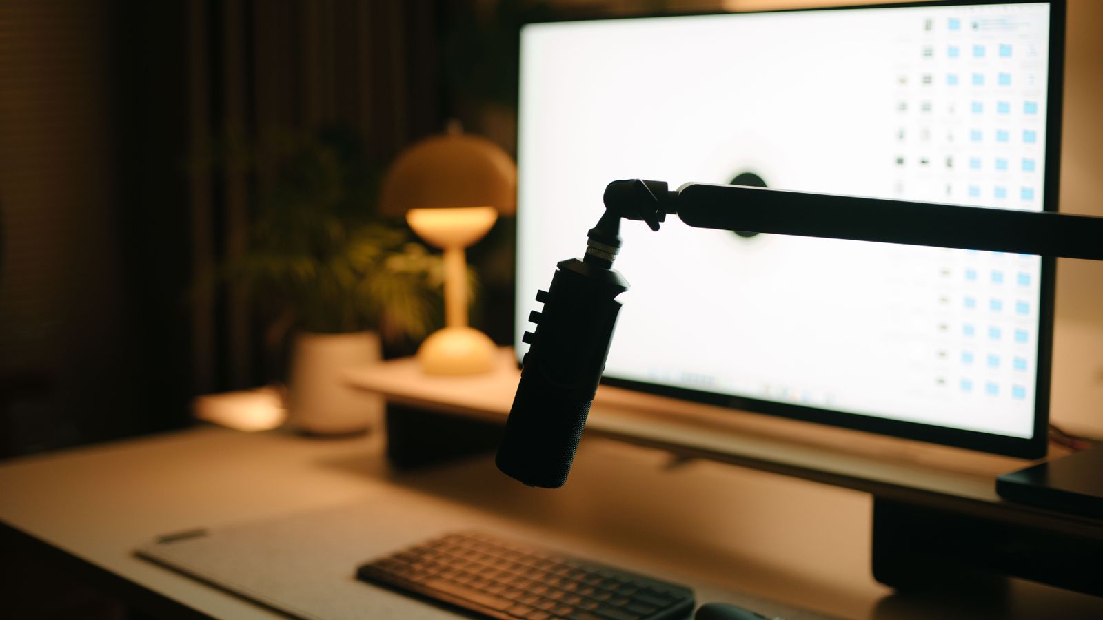 A warm and inviting workspace featuring a computer, microphone, and ambient lighting.