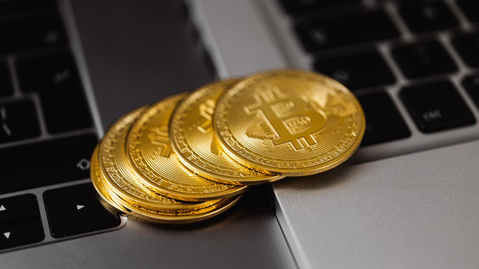 Close-up of golden bitcoins on a laptop keyboard representing digital currency and wealth.
