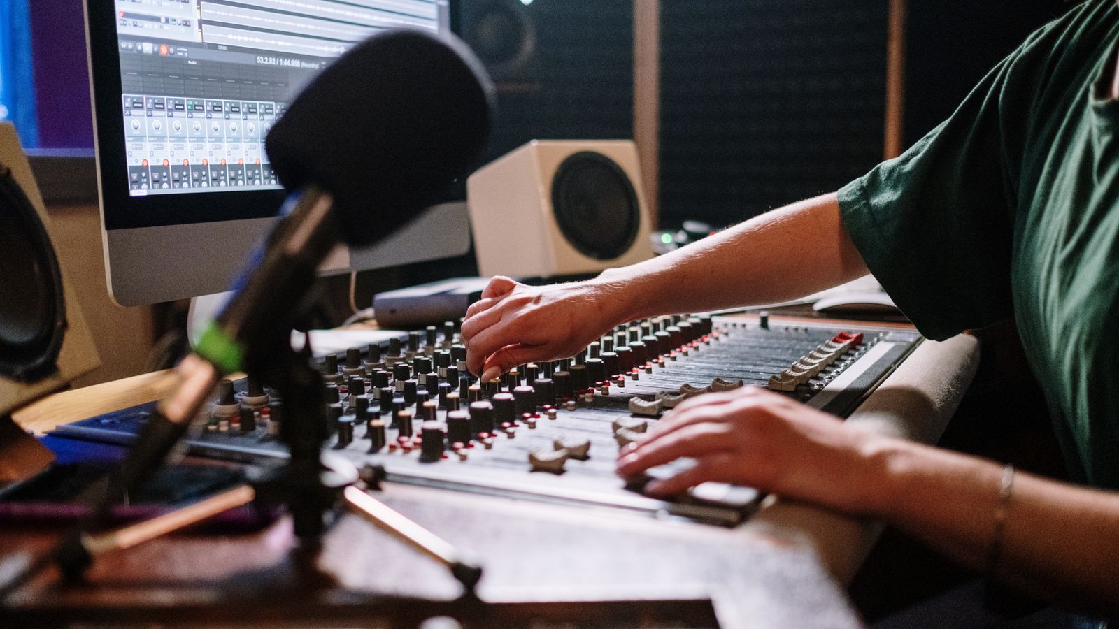 Professional audio engineer adjusting mixer in a modern sound studio.