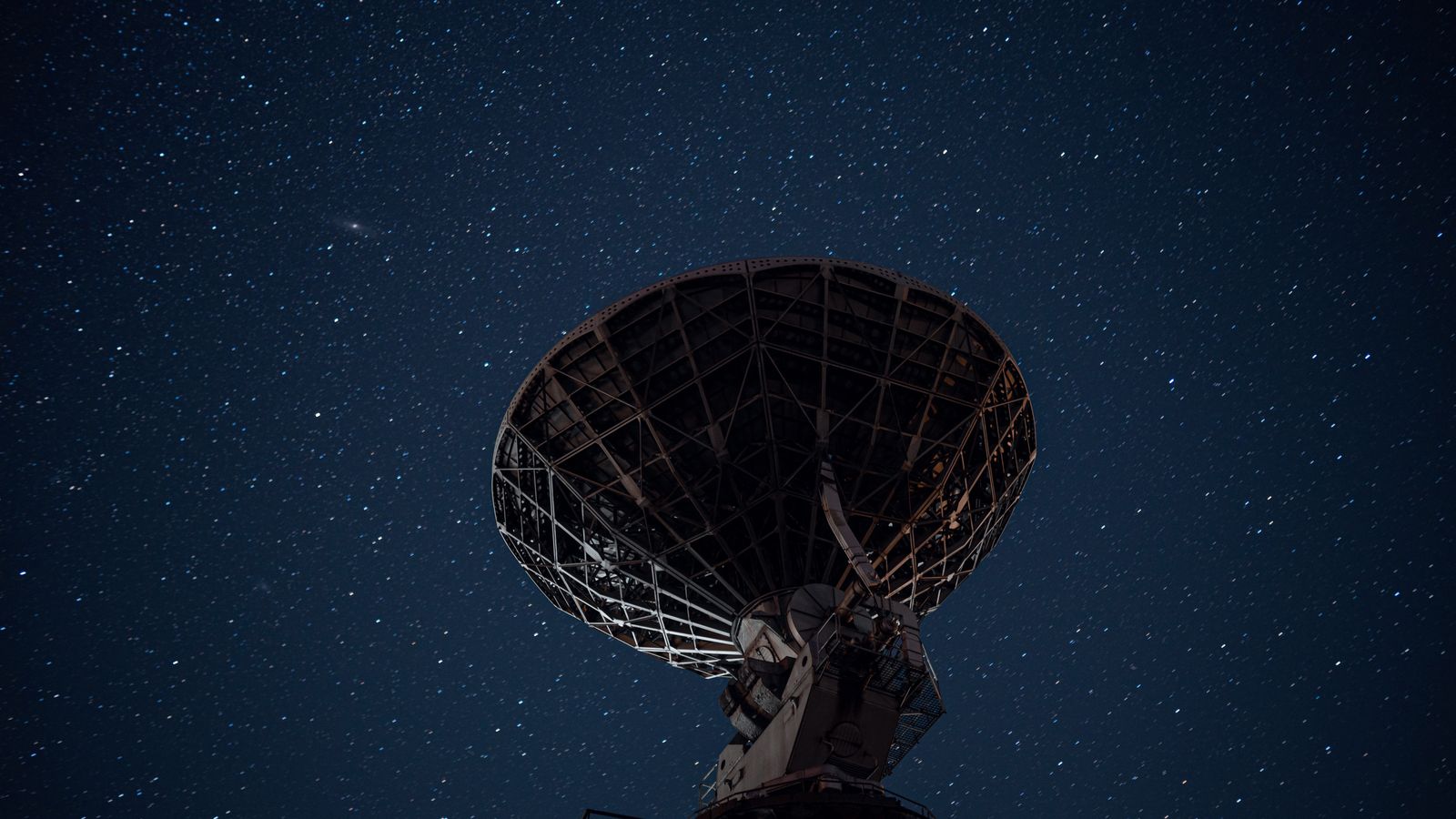 From below of high radio telescope under sky with glowing stars in dark night