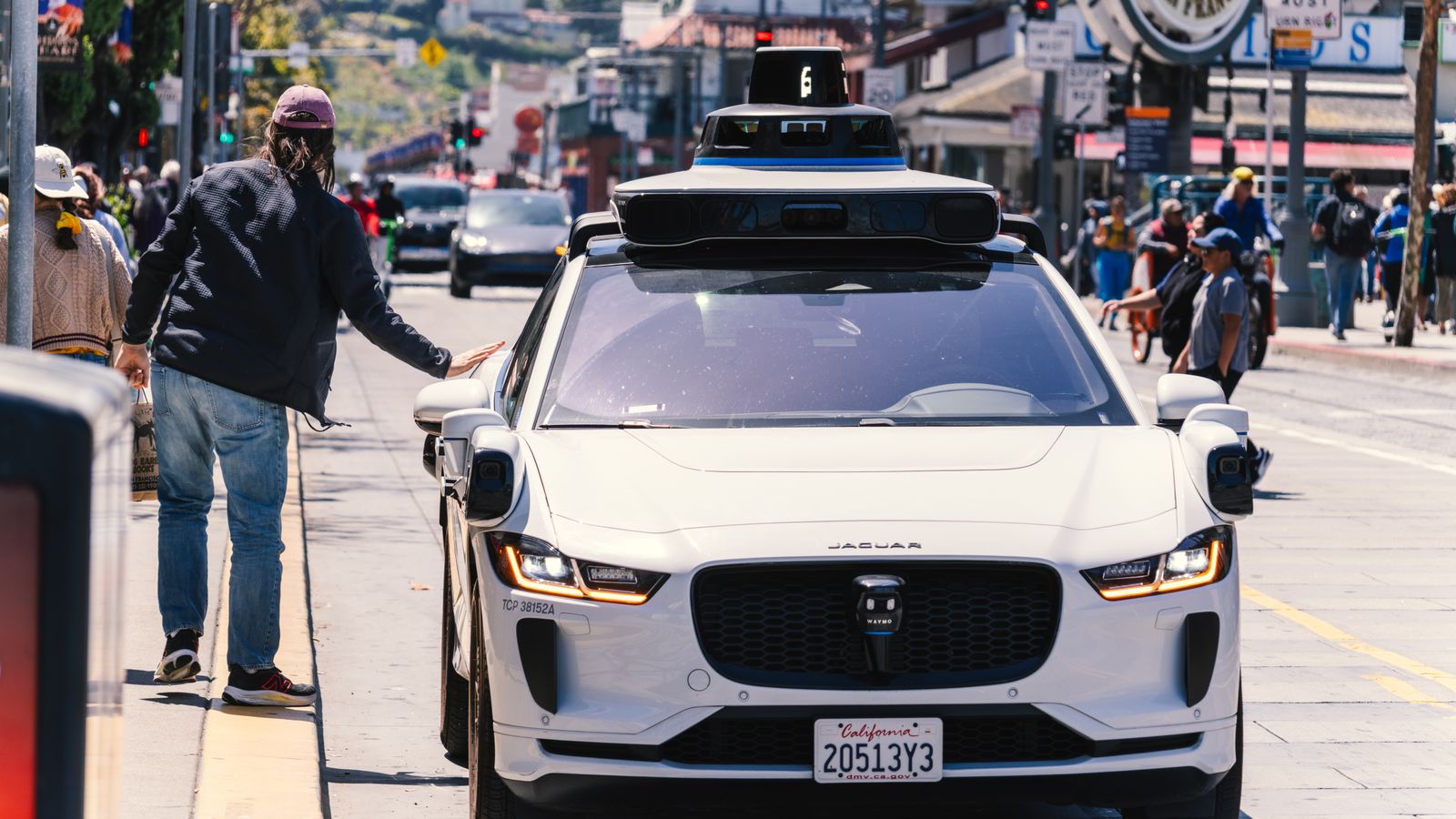 A self-driving car navigates through a bustling city street in San Francisco, capturing urban mobility in action.