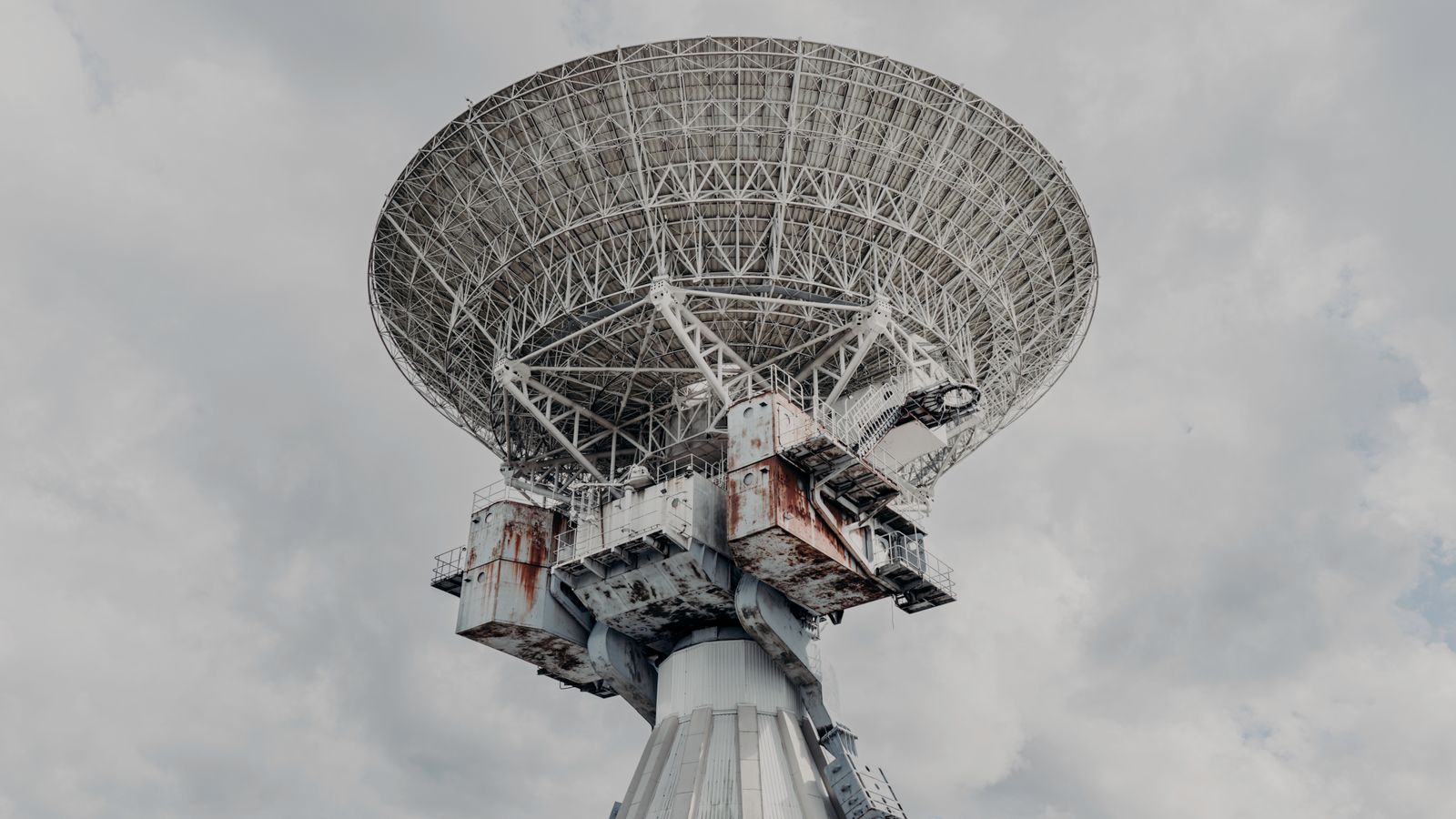 Close-up of a large radio telescope against a cloudy sky.