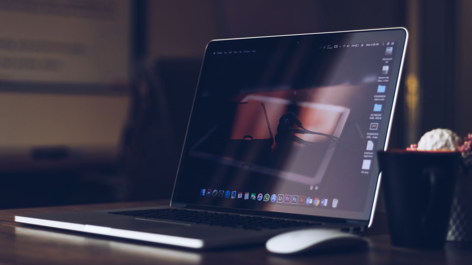 A sleek laptop on a wooden desk with a cup, creating a warm and cozy workspace atmosphere.