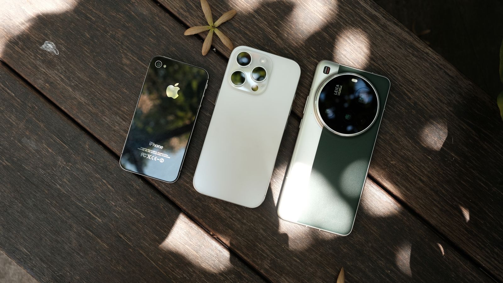 Three modern smartphones displayed on a wooden surface with natural lighting.