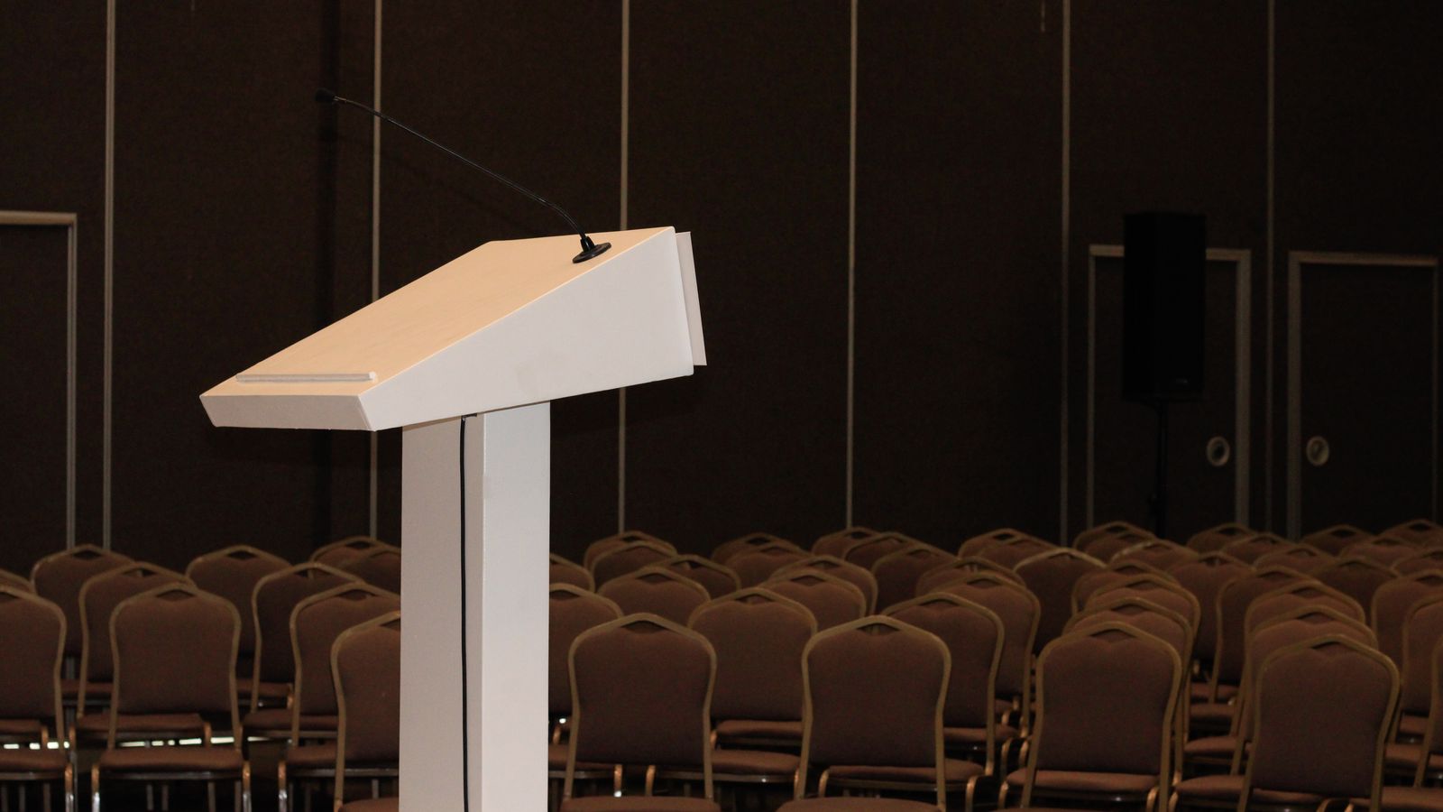 Colorful rows of empty red and burgundy chairs in an auditorium setting.